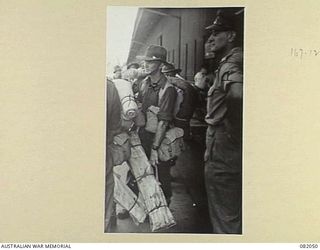 CAIRNS, QLD. 1944-10-28. LIEUTENANT-COLONEL N.W.P. FARRELL, COMMANDING OFFICER 2/4 INFANTRY BATTALION (1), WATCHES HIS MEN BOARDING THE USS MEXICO DURING EMBARKATION FOR NEW GUINEA. IDENTIFIED ..