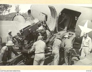 1943-06-25. NEW GUINEA. A U.S. ANTI-AIRCRAFT UNIT LOADS A 40MM BOFORS GUN INTO A DOUGLAS C47 TRANSPORT AIRCRAFT OF THE US ARMY AIR FORCE