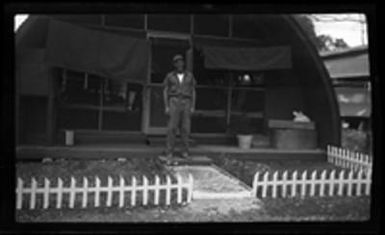 [Serviceman Benny Schotten in front of Quonset hut]