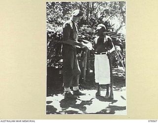 BOUGAINVILLE AREA. 1945-01-22. NX49798 CAPTAIN R. WATSON, MBE, HEADQUARTERS, AUSTRALIAN AND NEW GUINEA ADMINISTRATIVE UNIT ACCEPTING CAPTURED JAPANESE DOCUMENTS FROM MOSIAMA, THE ORGANISER OF AN ..