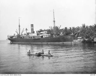 THE S.S. MATUNGA, THE FIRST COMMERCIAL SHIP TO ARRIVE AFTER THE OCCUPATION BY THE AUSTRALIAN NAVY AND MILITARY EXPEDITIONARY FORCE (AN&MEF), AT MADANG WHARF, IN WHAT WAS FORMERLY GERMAN NEW GUINEA, ..