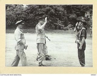 TOROKINA, BOUGAINVILLE. 1945-03-30. LORD WAKEHURST, GOVERNOR OF NEW SOUTH WALES (1), WITH LIEUTENANT-GENERAL S.G. SAVIGE, GENERAL OFFICER COMMANDING 2 CORPS (2), BEING GREETED BY MAJOR W. MCCALL, ..