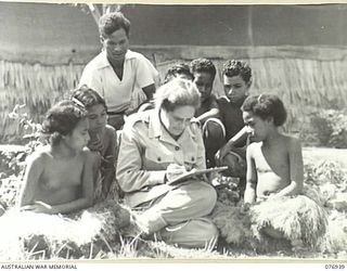 MORESBY AREA, PAPUA. 1944-11-23. VF515041 LIEUTENANT-COLONEL C.H. WEDGEWOOD, DIRECTORATE OF RESEARCH (ANTHROPOLOGY), LAND HEADQUARTERS, AUSTRALIAN MILITARY FORCES, WITH NATIVE CHILDREN