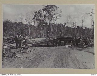 WARINGE RIVER, WEWAK AREA, NEW GUINEA, 1945-05-13. SAPPERS OF 8 PLATOON, 2/8 FIELD COMPANY, ROYAL AUSTRALIAN ENGINEERS, CONSTRUCTING A PERMANENT BRIDGE BESIDE A TEMPORARY PONTOON BRIDGE OF FOLDING ..