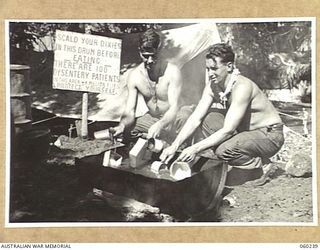 DUMPU, NEW GUINEA. 1943-11-05. SX9739 PRIVATE W. D. MORGAN (LEFT) AND NX3354 CORPORAL R. F. HARRIS (RIGHT) OF THE 2/6TH AUSTRALIAN FIELD AMBULANCE WASHING THEIR DIXIES AT THE MAIN DRESSING STATION. ..