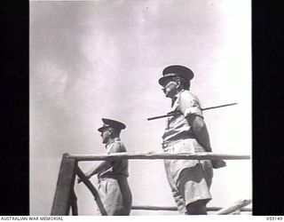 KILA, NEW GUINEA. 1943-10-24. PX134 LIEUTENANT COLONEL S. ELLIOTT-SMITH (LEFT) ADDRESSING NATIVES AT THE NATIVE LABOUR CAMP, WHILST PP1 MAJOR GENERAL B. M. MORRIS DSO, GENERAL OFFICER COMMANDING, ..