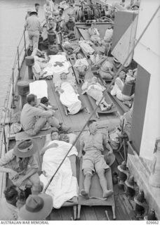 PORT MORESBY, PAPUA. 1942-09. AUSTRALIANS WOUNDED IN THE FIGHTING IN NEW GUINEA BEING FERRIED BY THE CORVETTE H.M.A.S. BENDIGO OUT TO THE HOSPITAL SHIP MANUNDA, WHICH IS LYING OUT IN THE HARBOUR