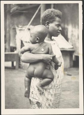 Woman holding a baby wearing a Mission Medal, New Guinea, ca. 1936 / Sarah Chinnery