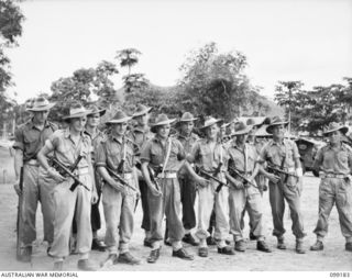RABAUL, NEW BRITAIN, 1945-11-30. AN AUSTRALIAN ARMY GUARD, DRAWN FROM 28 INFANTRY BATTALION, 13 INFANTRY BRIGADE, ARMED WITH OWEN SUBMACHINE GUNS. THEY WATCHED OVER THE SUSPECTED JAPANESE WAR ..