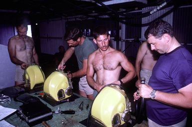 Navy divers from Mobile Diving Salvage Unit One check their Mark 12 dive helmets prior to final fitting in the dive platform workshop. The divers are preparing to study the wreck of the World War II Japanese merchant ship KIZUGAWA MARU as part of Project Sea Mark, a four-year undersea survey and mapping study of naval historic sites. The study is being conducted in conjuction with the U.S. Park Service's Submerged Cultural Resource Unit