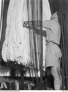 3 MILE, PORT MORESBY, NEW GUINEA. 1943-12-14. SX26055 LIEUTENANT L. G. GURNER, OFFICER COMMANDING, 1ST AUSTRALIAN PARACHUTE REFOLDING PLATOON, AUSTRALIAN ARMY ORDNANCE CORPS, INSPECTING A LARGE 48 ..