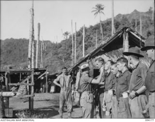 BOIKEN, NEW GUINEA. 1945-07-15. LIEUTENANT J.J. GARRICK, 2/6 CAVALRY (COMMANDO) REGIMENT (1), PLACING TABLETS IN THE MOUTHS OF TROOPS DURING THE "ATEBRIN" PARADE. ATEBRIN WAS AN ANTI-MALARIA DRUG ..