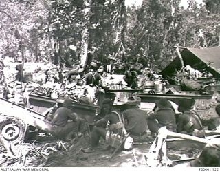 THE SOLOMON ISLANDS, 1945-04-24/27. A MIXTURE OF AUSTRALIAN SERVICEMEN, NATIVES AND LADEN TRAILERS AT A CAMP SITE ON BOUGAINVILLE ISLAND. (RNZAF OFFICIAL PHOTOGRAPH.)