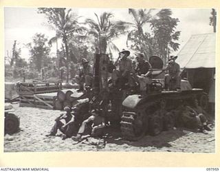WEWAK BEACH, NEW GUINEA. 1945-10-18. MEMBERS OF 8 PORT OPERATING COMPANY SITTING ON A JAPANESE TYPE 97 CHI-HA MEDIUM TANK HAVING TEA. THEY SUPERVISE THE BERTHING AND UNLOADING OF CARGO AT WEWAK ..