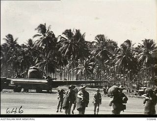 PAPUA-NEW GUINEA AREA. 1944-02-04. RAAF PERSONNEL WALKING ACROSS AN AIRFIELD WITH THEIR KITBAGS ON THEIR ARRIVAL IN NEW GUINEA AFTER A FLIGHT IN A RAAF DOUGLAS C47 DAKOTA TRANSPORT AIRCRAFT