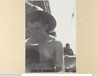 AT SEA, NEW GUINEA AREA, 1944-11-12. PRIVATE B. MEREDITH, HEADQUARTERS 6 DIVISION, READING "THE AUSTRALIAN SOLDIERS' POCKET BOOK" ABOARD USS MEXICO DURING MOVEMENT TO AN OPERATIONAL AREA. THE BOOK, ..