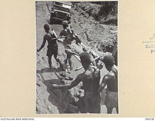 SOUTH BOUGAINVILLE. 1945-07-21. NATIVE CARRIERS SQUELCHING THROUGH MUD EVACUATING A BATTLE CASUALTY OF 15 INFANTRY BATTALION TO THE MAIN DRESSING STATION WEST OF THE OGORATA RIVER. TWENTY INCHES OF ..