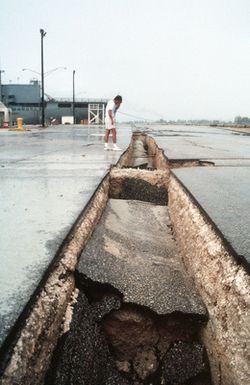 Peter Wagner, a local journalist, looks at a large split in the pavement caused by an earthquake that struck the area on August 8th