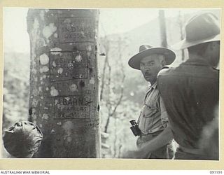 NUMA NUMA TRAIL, BOUGAINVILLE. 1945-04-24. LIEUTENANT COLONEL A. POPE, COMMANDING OFFICER, 27 INFANTRY BATTALION, AT AN ADVANCED LISTENING POST. ON A NEARBY TREE CAN BE SEEN NAMES OF THREE MEN WHO ..
