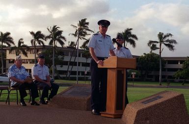 During a twilight ceremony, COL. Bruce Brown, Commander of the 15th Air Base Wing, speaks in memory of those who gave their lives on December 7, 1941. Standing beside COL. Brown is attack survivor Robert May of the 11th Bombardment Wing. Seated in the background are Chaplain Thomas Kelly and MAJ. Joseph Davis