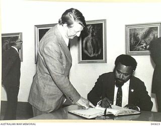 AUSTRALIAN WAR MEMORIAL, CANBERRA, ACT 1976-03-04. MR N.J. FLANAGAN, DIRECTOR, AUSTRALIAN WAR MEMORIAL WATCHING MR MICHAEL SOMARE, PRIME MINISTER OF PAPUA NEW GUINEA SIGN THE VISITOR'S BOOK ON THE ..