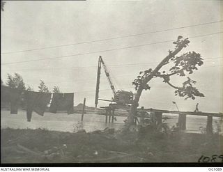 AITAPE, NORTH EAST NEW GUINEA. C. 1944-06. A NEW BRIDGE BEING BUILT ACROSS THE RAIHU RIVER BY NO. 7 MOBILE WORKS SQUADRON RAAF. NOTE THE WASHING HUNG BETWEEN THE TREES IN THE FOREGROUND