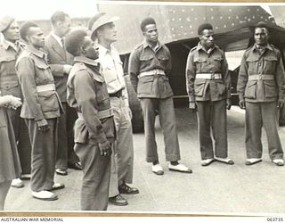 ALEXANDRIA, NSW. 1944-01-24. AUSTRALIAN AND NEW GUINEA ADMINISTRATION UNIT NATIVES WATCHING THE CONSTRUCTION OF WOODEN LANDING BARGES AT SLAZENGER'S FACTORY