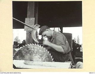 BUSU FOREST, LAE AREA, NEW GUINEA. 1944-07-26. THE TEETH OF A SAW BEING SET AT THE 2/3RD FORESTRY COMPANY, ROYAL AUSTRALIAN ENGINEERS