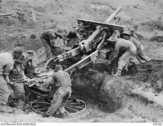 WEWAK AREA, NEW GUINEA, 1945-06-07. TROOPS OF 2/3 FIELD REGIMENT, ROYAL AUSTRALIAN ARTILLERY, MANHANDLING A 25-POUNDER INTO POSITION IN A NEWLY CONSTRUCTED GUN PIT AT THE REAR OF THE BORAM STRIP, ..