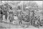 Pig festival, pig sacrifice, Kompiai: man holds up kina shell valuable for exchange, display mat at left