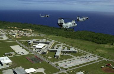 Two UH-46 Sea Knights and a pair of UH-60 Black Hawk helicopters assigned to Andersen Air Force Base (AFB), Guam, fly over their home near the Pacific Ocean