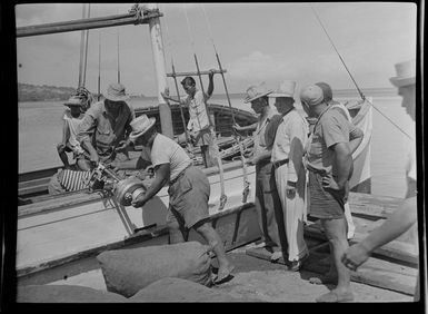 Waterfront scene, men by boat, equipments and goods being loaded [off or on?] boat, Tahiti