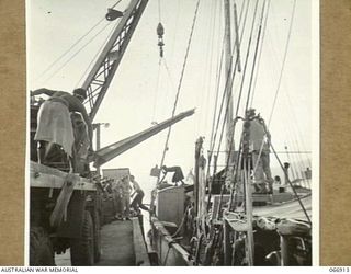 PORT MORESBY, NEW GUINEA. 1944-06-14/02. NATIVES LOADING STEEL RAILS ON TO THE AK94 A VESSEL OF THE 12TH SMALL SHIPS COMPANY. THESE RAILS ARE TO BE USED IN THE CONSTRUCTION OF THE NEW DOCKS AT LAE