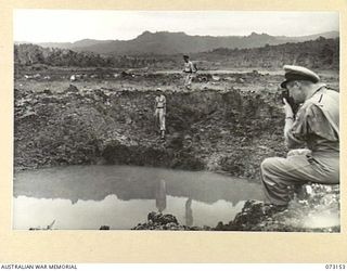 ALEXISHAFEN, NEW GUINEA. 1944-05-11. MEMBERS OF A RMSU (RENDERING MINES SAFE UNIT) RAN, EXAMINING A LARGE CRATER AT THE ALEXISHAFEN NO. 1 AIRSTRIP. THE CRATER IS BELIEVED TO HAVE BEEN CAUSED BY THE ..