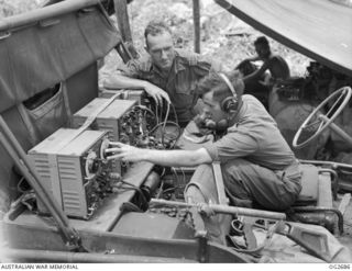 BUT AREA, DAGUA, NORTH EAST NEW GUINEA. C. 1945-04. MEMBERS OF A FRONT LINE RAAF MOBILE UNIT IN TOUCH BY WIRELESS/RADIO EQUIPMENT WITH A RAAF BOMBER AIRCRAFT FORMATION WHICH HAD BEEN POUNDING A ..