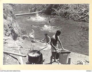 KEKRE CREEK, BOUGAINVILLE. 1945-08-30. MEMBERS OF 2/4 ARMOURED REGIMENT WORKSHOP SWIMMING IN THE CREEK. PORTABLE LAUNDRY OPERATING IN FOREGROUND