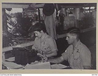 LAE, NEW GUINEA. 1945-05-15. GUNNER S.M. BRENNAN (1), AT "A" BRANCH, HEADQUARTERS FIRST ARMY RECEIVING INSTRUCTION IN HER NEW JOB FROM CORPORAL R. FISHER (2). A FEW DAYS AFTER THEIR ARRIVAL FROM ..