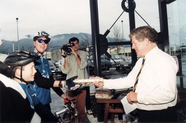 Mayor Rex Kirton receives Commonwealth Games official baton from cyclists Phillip Cantwell, Gavin McArthur.