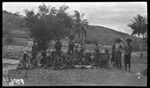 Lambert's assistants on right, administering hookworm treatment to group of men and boys