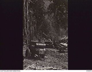 BULLDOG-WAU ROAD, NEW GUINEA, 1943-07-10. THE 10 MILE CAMP OF THE ROYAL AUSTRALIAN ENGINEERS, HEADQUARTERS, 11TH AUSTRALIAN DIVISION SHOWING COOKHOUSE, ROAD VEHICLES, AIR COMPRESSOR AND A SMALL ..