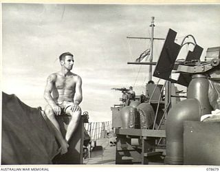 AT SEA. 1945-01-28. ABLE SEAMAN A.A. THOMPSON RELAXING IN THE SUN ON THE DECK OF ML802 OF THE ROYAL AUSTRALIAN NAVY PORT DIRECTORAE, JACQUINOT BAY