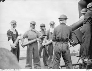 The gun crew firing the 4 inch Mark XIX gun on a Mark XXIII mounting aboard the RAN Corvette Geelong, while on convoy duty off the New Guinea coast