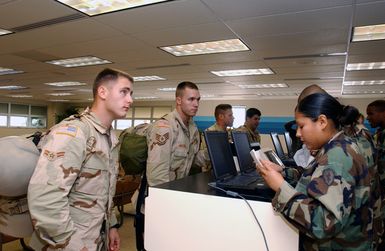 Left to right, US Air Force (USAF) AIRMAN First Class (A1C) Nathan Bryant, STAFF Sergeant (SSGT) Lance Mitchel, SSGT Warren Williams and SSGT Craig Lower, all members of the 25th Air Support Operations Squadron (ASOS), receive their boarding passes at the Hickam Air Force Base (AFB) Hawaii, passenger counter