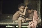 Boys play on house veranda, one picks nits from the other's hair