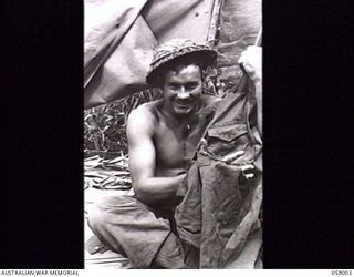 DUMPU, NEW GUINEA. 1943-10-15. SX31562 PRIVATE R. K. BARNES OF NO. 7 PLATOON, "A" COMPANY, 2/27TH AUSTRALIAN INFANTRY BATTALION WITH HIS FINGERS THROUGH A HOLE IN HIS SHIRT CAUSED BY SHRAPNEL FROM ..