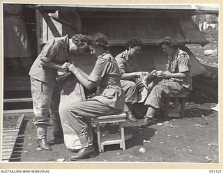 LAE, NEW GUINEA, 1945-05-08. AWAS PERSONNEL SETTLING AT THE NEWLY CONSTRUCTED AWAS BARRACKS IN BUTIBUM ROAD, MAKING BEDSIDE MATS BY SPLITTING HESSIAN BAGS IN TWO AND BINDING THE EDGES. THE GIRLS ..