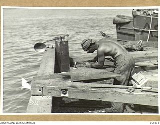 LAE, NEW GUINEA, 1943-11-05. ASN-32787887 T/5 B.S. ELMO OF THE 1052ND ENGINEERS PORT CONSTRUCTION AND REPAIR GROUP FLAME CUTTING A STEEL PLATE TO BE USED IN THE CONSTRUCTION OF THE FIRST LIBERTY ..