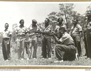 SOUTHPORT, QLD. 1944-01-18. A NEW GUINEA POLICE BOY FIRING A .303 RIFLE AT A TANK OF THE 4TH ARMOURED BRIGADE DURING A DEMONSTRATION OF STRENGTH OF THE ARMOUR PLATING