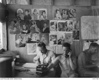 NADZAB, NEW GUINEA. 1944-05-09. MEMBERS OF A RAAF TRANSPORT MOVEMENTS OFFICE CLAIM TO HAVE ONE OF THE BEST PIN-UP COLLECTIONS IN THE AREA - AND ALL THE GIRLS HAVE CLOTHES ON! HERE THE BOYS HAVE ..