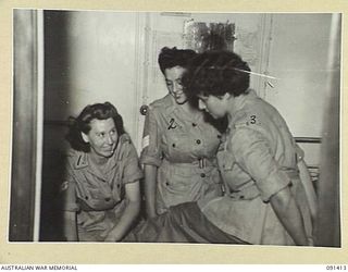 LAE, NEW GUINEA, 1945-05-07. AUSTRALIAN WOMEN'S ARMY SERVICE PERSONNEL ASSISTING EACH OTHER WITH GAITERS BEFORE DISEMBARKATION FROM THE MV DUNTROON. THEY ARE PART OF A GROUP OF 342 AUSTRALIAN ..